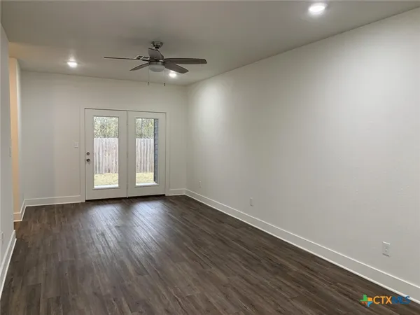 a view of an empty room with a window and wooden floor