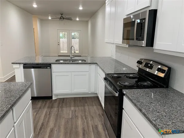 a kitchen with stainless steel appliances granite countertop a sink stove and cabinets