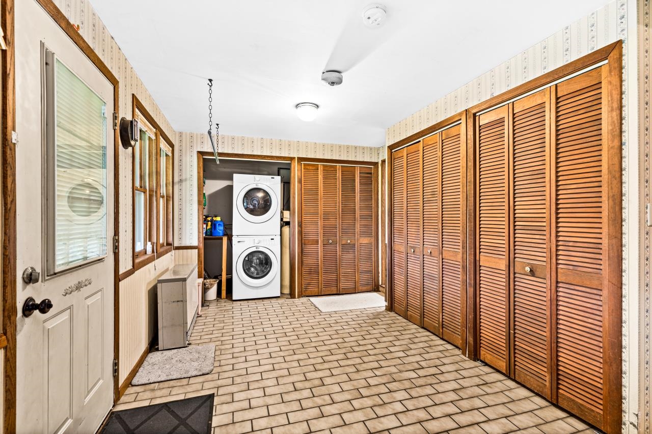 3723 Birchwood Road Kettle River, MN 55757 - Photo 12 of 48 Washroom with wallpapered walls, stacked washer and clothes dryer, brick patterned flooring, and wainscoting