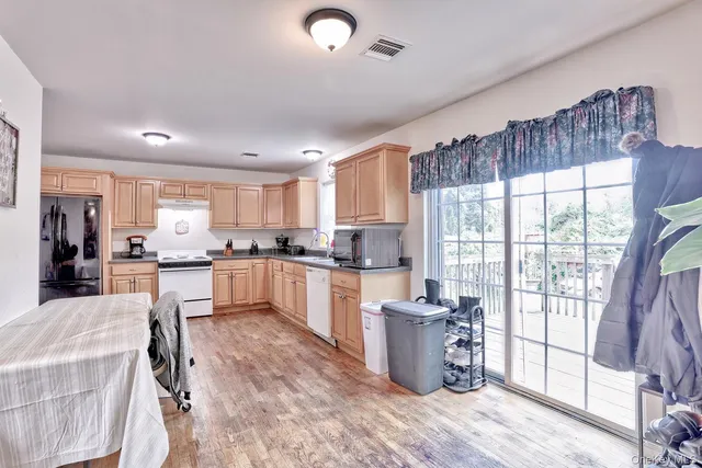 a large kitchen with kitchen island a large window cabinets a sink and stainless steel appliances