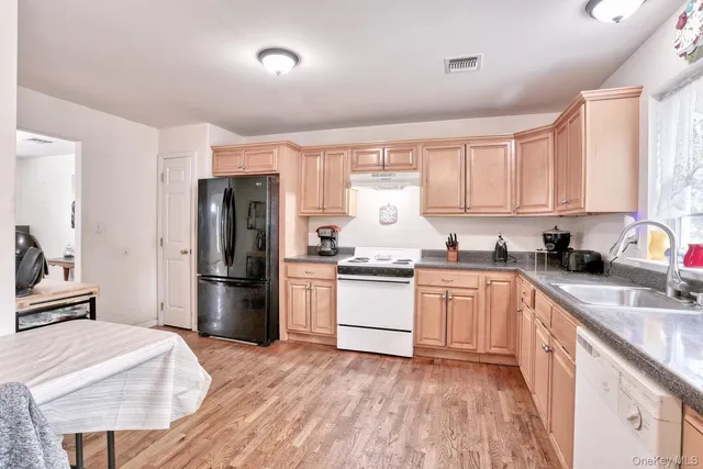 a kitchen with a refrigerator stove and sink with wooden floor