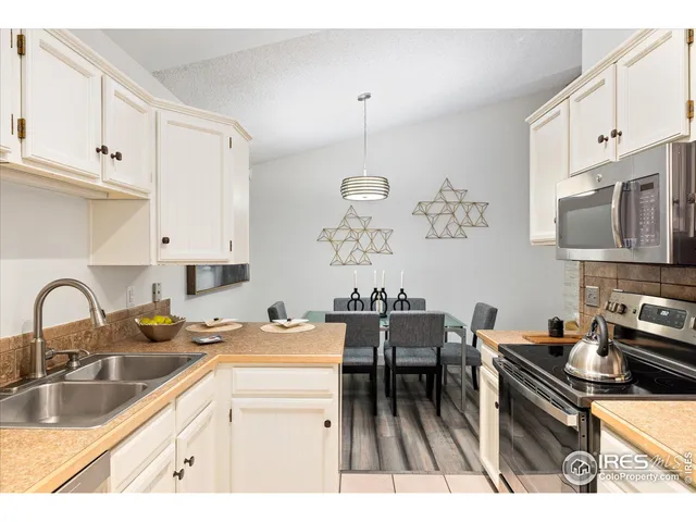 a kitchen with granite countertop a stove a sink a kitchen island with white cabinets and wooden floor