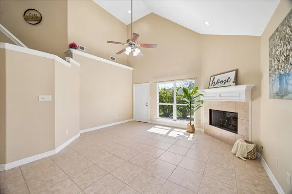 a view of a livingroom with a fireplace a ceiling fan and windows