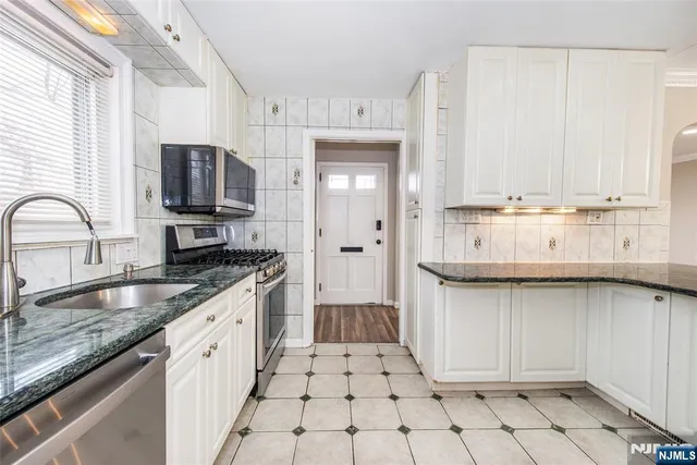 a large white kitchen with a sink and refrigerator