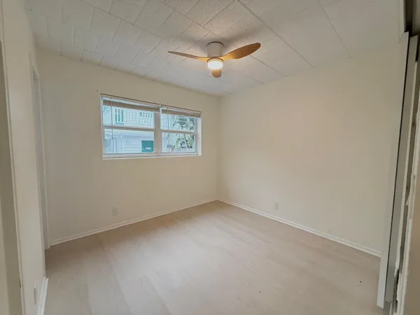 an empty room with a ceiling fan and windows