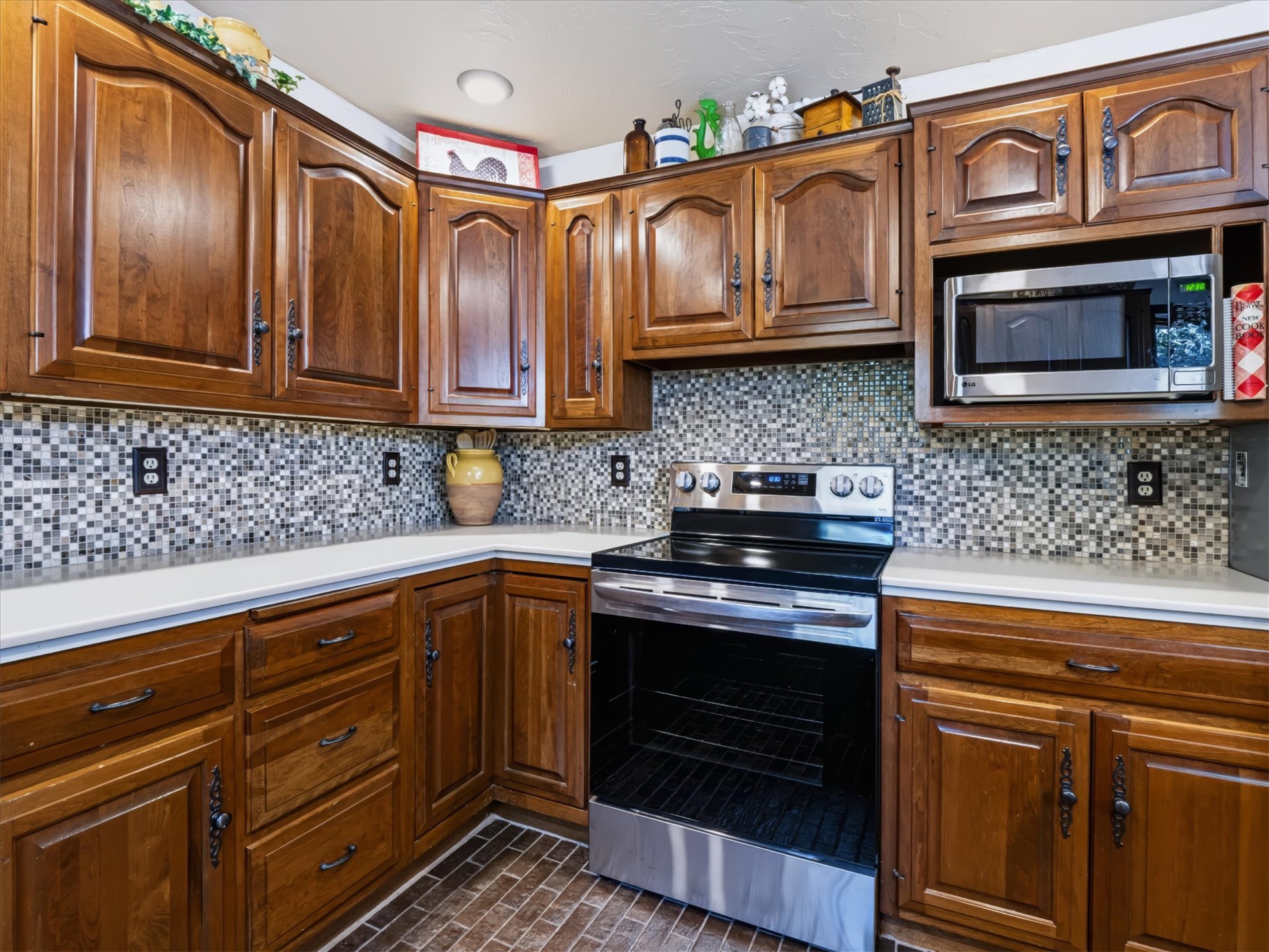 1133 West Chicken Fight Road Atoka, OK 74525 - Photo 22 of 49 Wood-finish cabinetry paired with white countertops, a mosaic tile backsplash, and stainless steel appliances