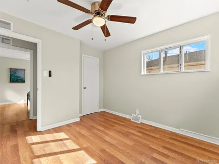 a view of empty room with wooden floor and fan