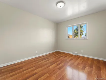an empty room with wooden floor and window