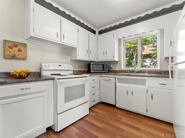 a kitchen with granite countertop white cabinets and white appliances