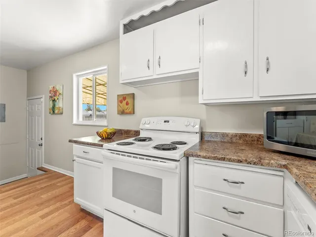 a kitchen with granite countertop white cabinets and white appliances