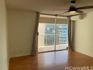 a view of empty room with wooden floor and fan