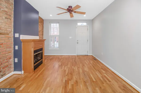 a view of a livingroom with a fireplace a ceiling fan and wooden floor