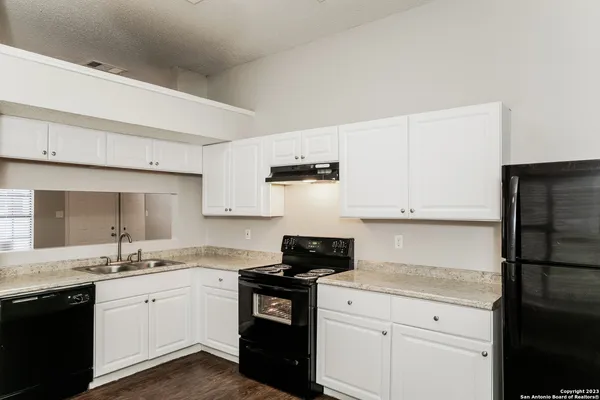 a kitchen with granite countertop white cabinets sink and stainless steel appliances