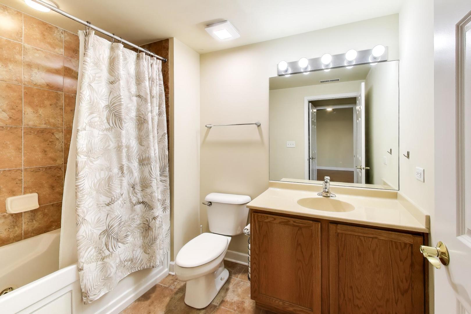 77 North Wolf Road, Unit 312 Northlake, IL 60164 - Photo 10 of 19 a bathroom with a sink a toilet and shower curtain