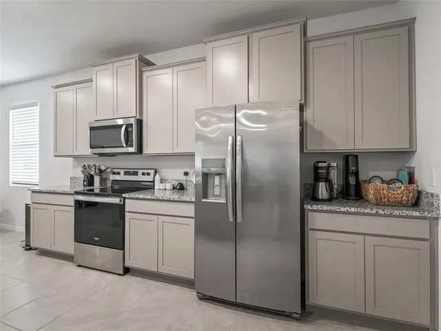 a kitchen with stainless steel appliances granite countertop a refrigerator a stove a sink and white cabinets