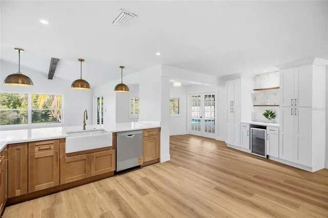 a large white kitchen with kitchen island a stove a refrigerator cabinets and a wooden floor