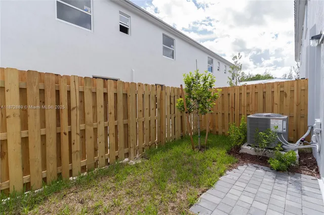 a backyard of a house with potted plants and wooden fence