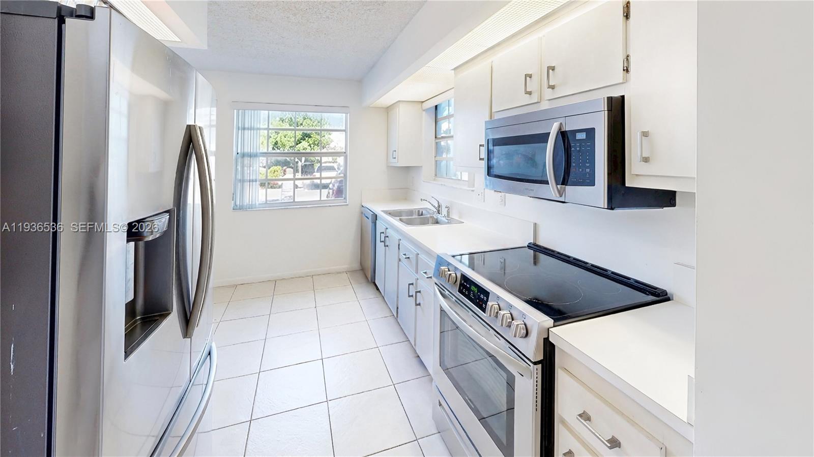 2657 Southeast 19th Court, Unit 103E Homestead, FL 33035 - Photo 14 of 50 a kitchen with a stove a sink and a refrigerator