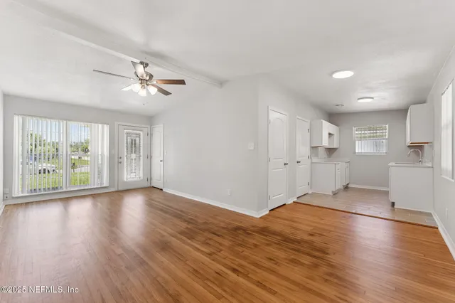 an empty room with wooden floor and windows
