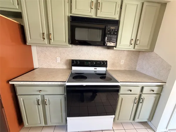 a kitchen with granite countertop a stove top oven microwave and cabinets