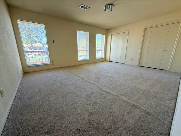 an empty room with windows and closet