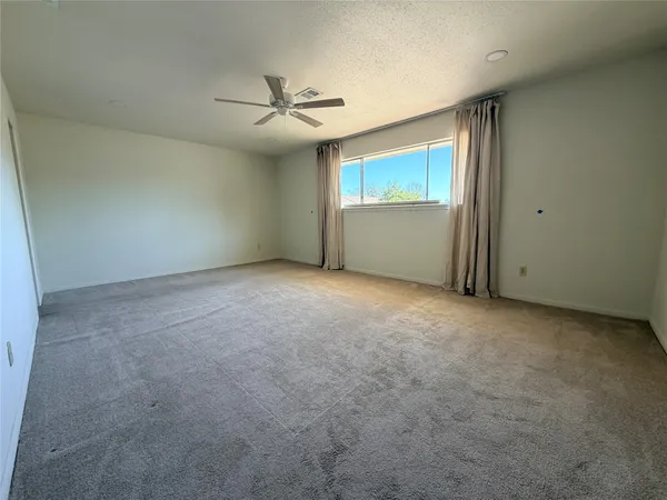 an empty room with windows and fan