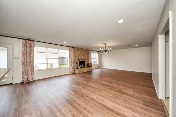 an empty room with wooden floor cabinet and windows