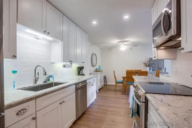 a kitchen with stainless steel appliances granite countertop a sink a stove and a wooden floors