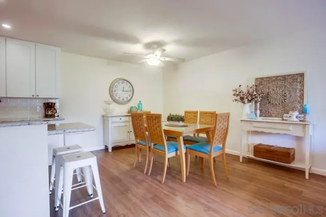 a living room with furniture a dining table wooden floor and a clock