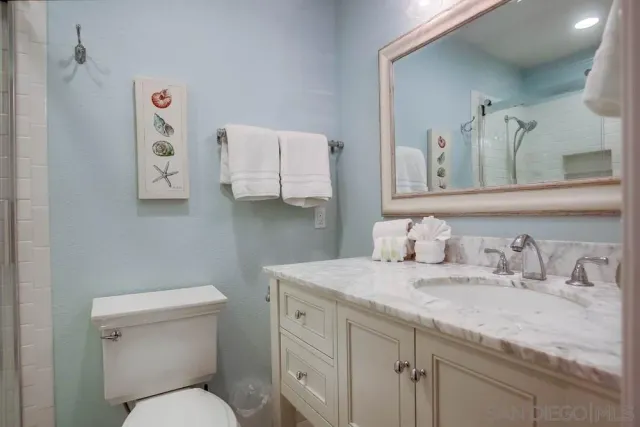 a bathroom with a granite countertop sink mirror vanity and toilet