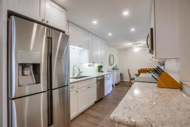 a kitchen with stainless steel appliances granite countertop a refrigerator a sink and a stove