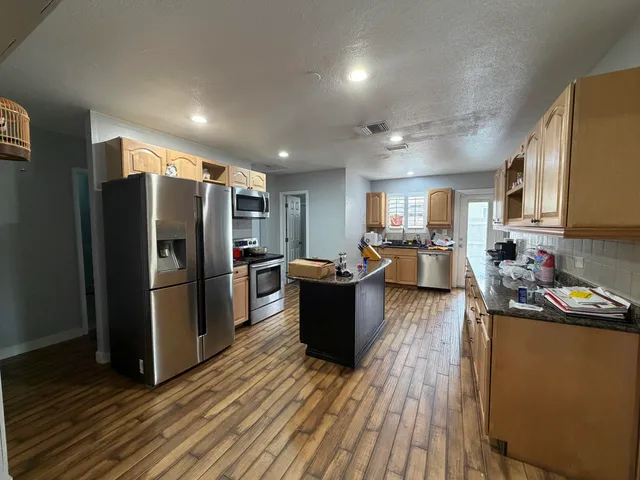 a kitchen with a refrigerator a stove top oven a sink dishwasher and wooden cabinets