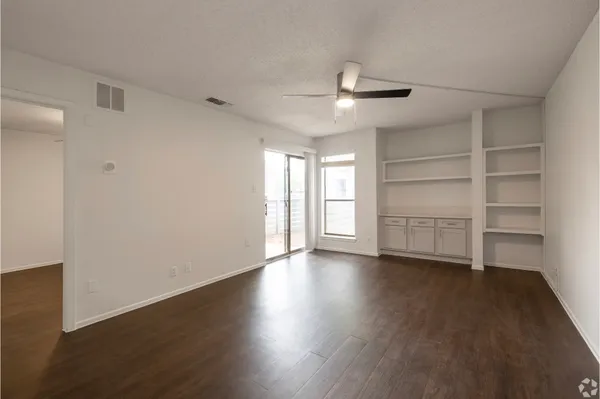 a view of an empty room with a window and wooden floor