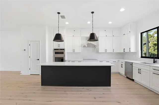 a kitchen with stainless steel appliances granite countertop a sink a stove and a wooden floor