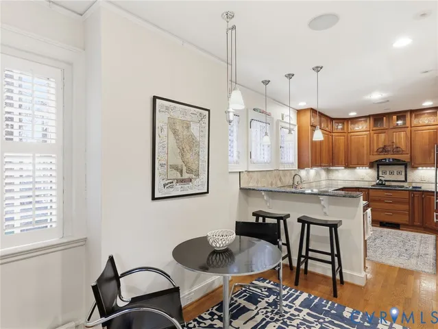 a kitchen with granite countertop a stove a sink a dining table and chairs with wooden floor