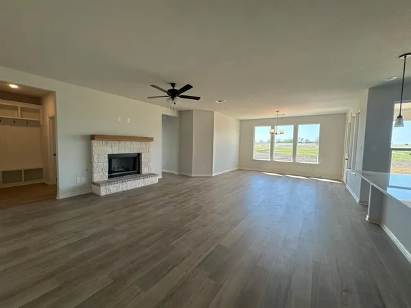 an empty room with wooden floor a fireplace and windows
