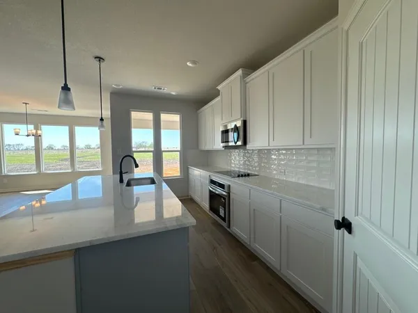 a kitchen with kitchen island granite countertop a sink a counter top space and cabinets