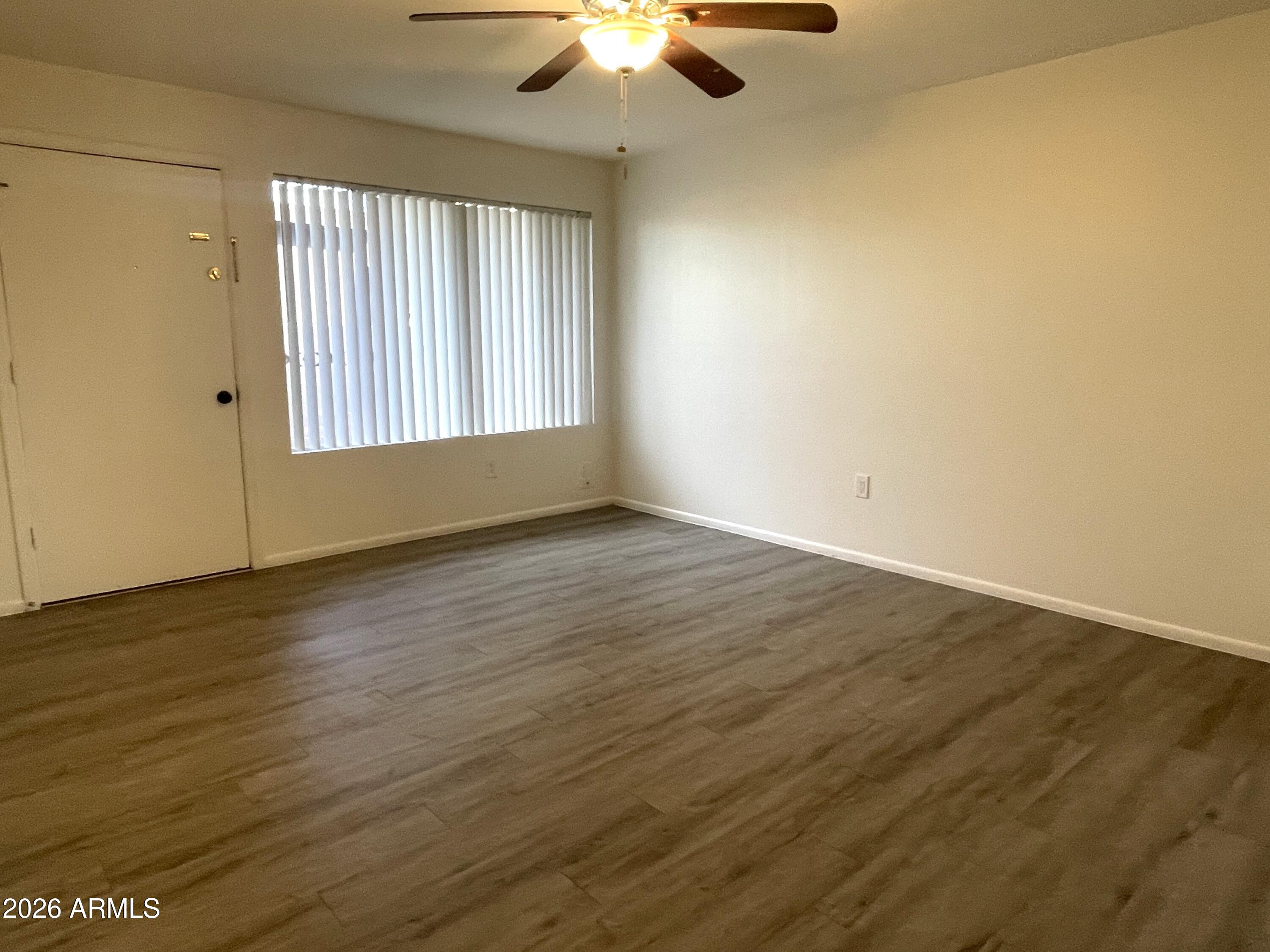 4719 North 15th Avenue, Unit 4 Phoenix, AZ 85015 - Photo 4 of 13 an empty room with wooden floor chandelier fan and windows