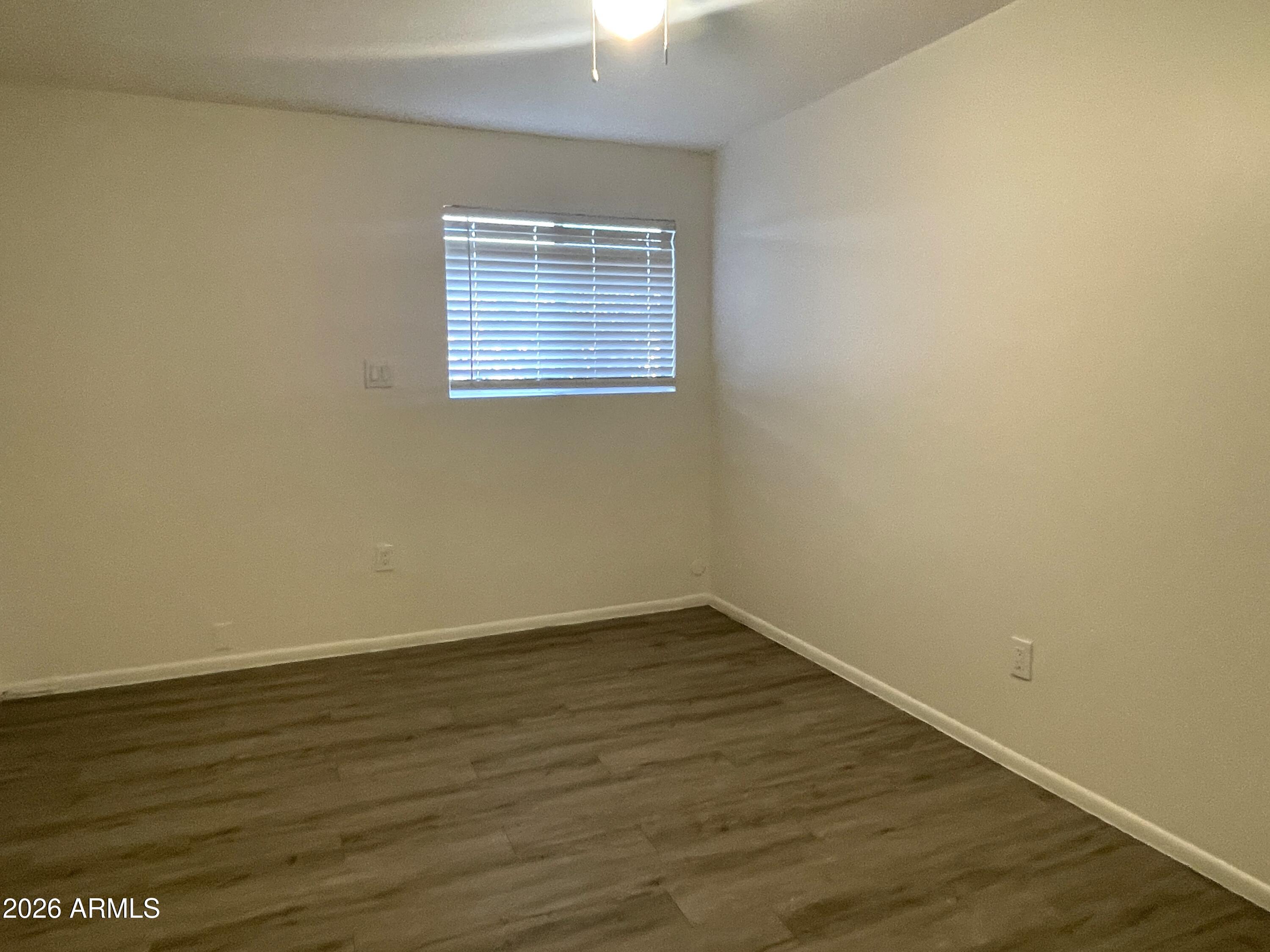 4719 North 15th Avenue, Unit 4 Phoenix, AZ 85015 - Photo 7 of 13 a view of an empty room with wooden floor and a window