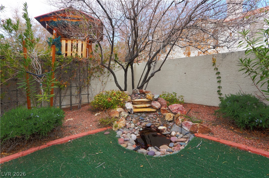 2108 Crestpoint Way Las Vegas, NV 89134 - Photo 26 of 27 A tranquil backyard retreat features a rock waterfall and a whimsical elevated playhouse.