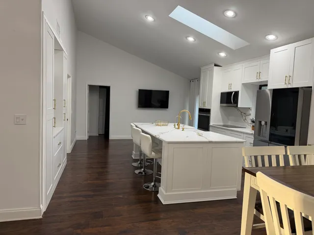 a living room with stainless steel appliances kitchen island granite countertop a sink and wooden floor