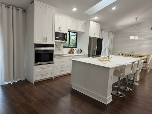 a kitchen with stainless steel appliances kitchen island granite countertop a stove a sink a microwave and a refrigerator