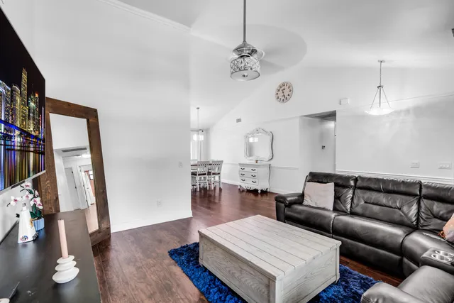a living room with furniture kitchen view and a wooden floor