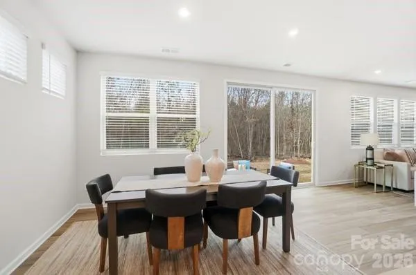 a kitchen with stainless steel appliances kitchen island granite countertop a dining table chairs and a refrigerator