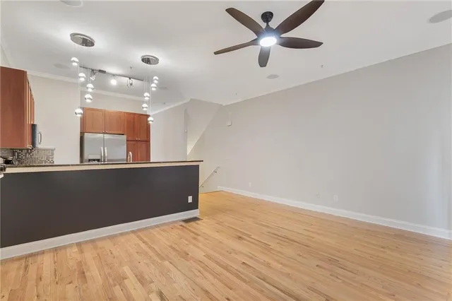 an empty room with wooden floor and a ceiling fan