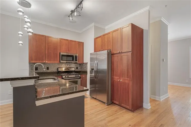a kitchen with granite countertop stainless steel appliances a refrigerator cabinets and wooden floor