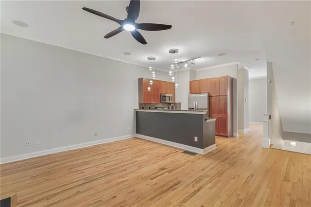 a view of kitchen and empty room with wooden floor