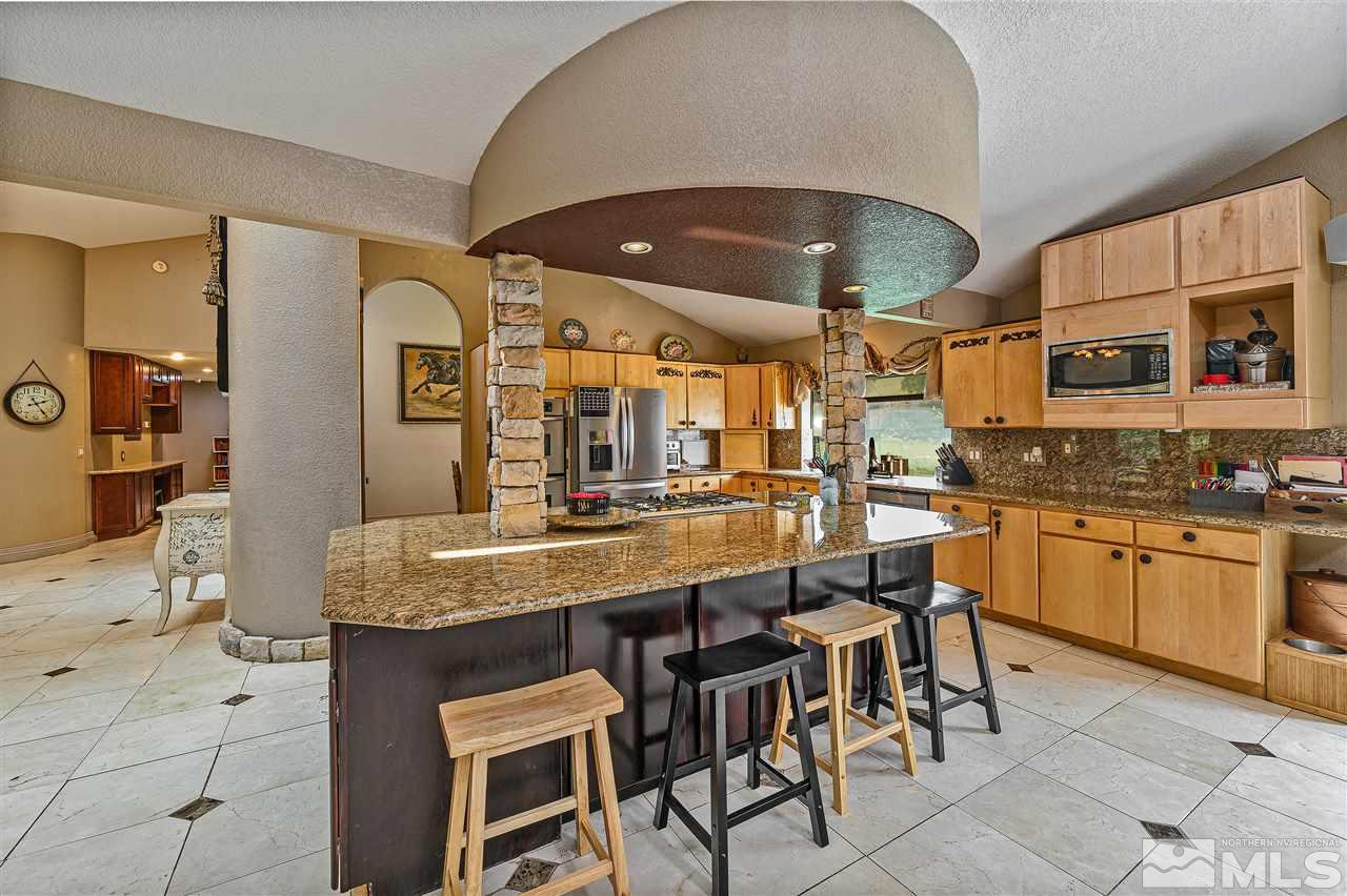 13040 Valley Springs Road Reno, NV 89511 - Photo 17 of 39 a kitchen with stainless steel appliances granite countertop a sink a stove and chairs