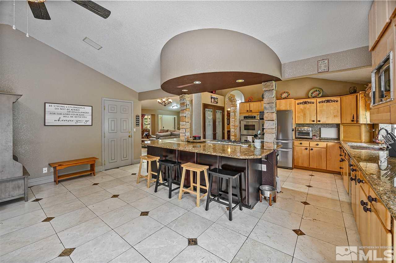 13040 Valley Springs Road Reno, NV 89511 - Photo 18 of 39 a dining hall with stainless steel appliances kitchen island granite countertop a table and chairs in it