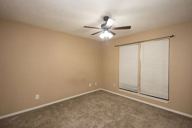 an empty room with a window and a fan